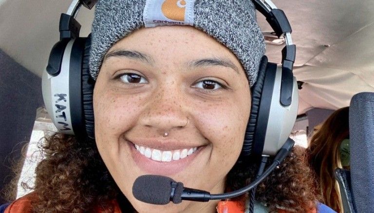 female student wearing headphones and mic in a helicopter 